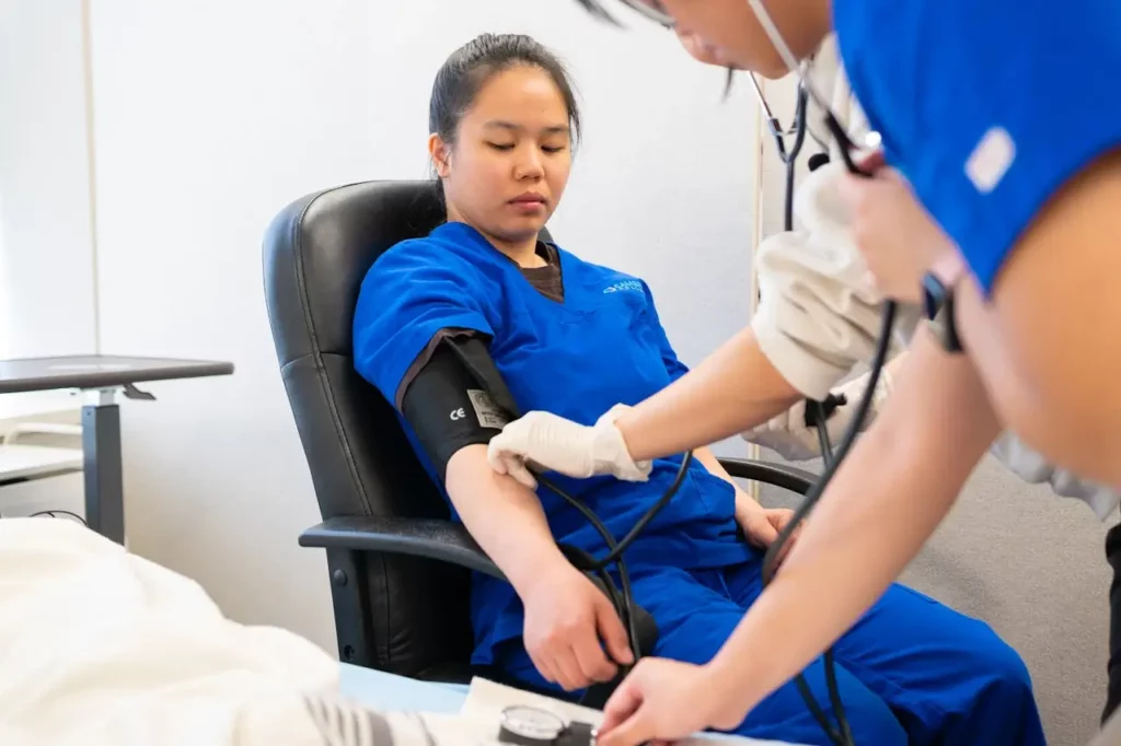 CNA student practicing blood pressure measurement during a clinical skills training session.