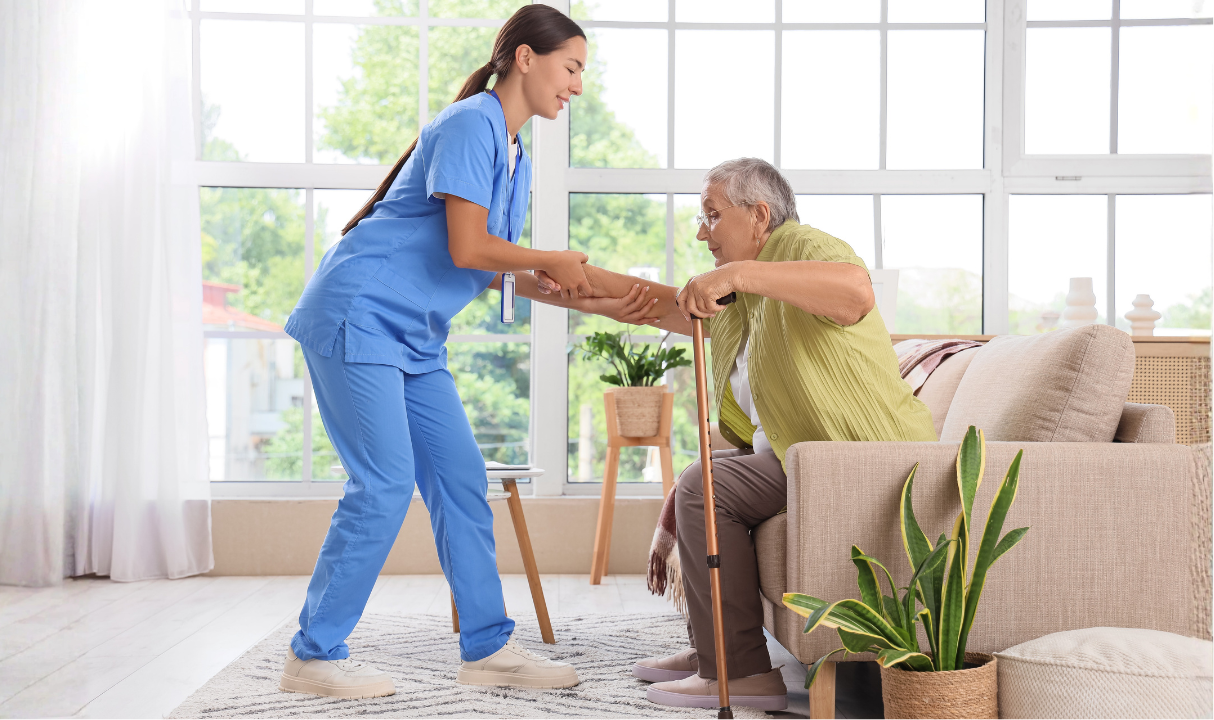 Home health aide helping a senior stand up safely in a home setting