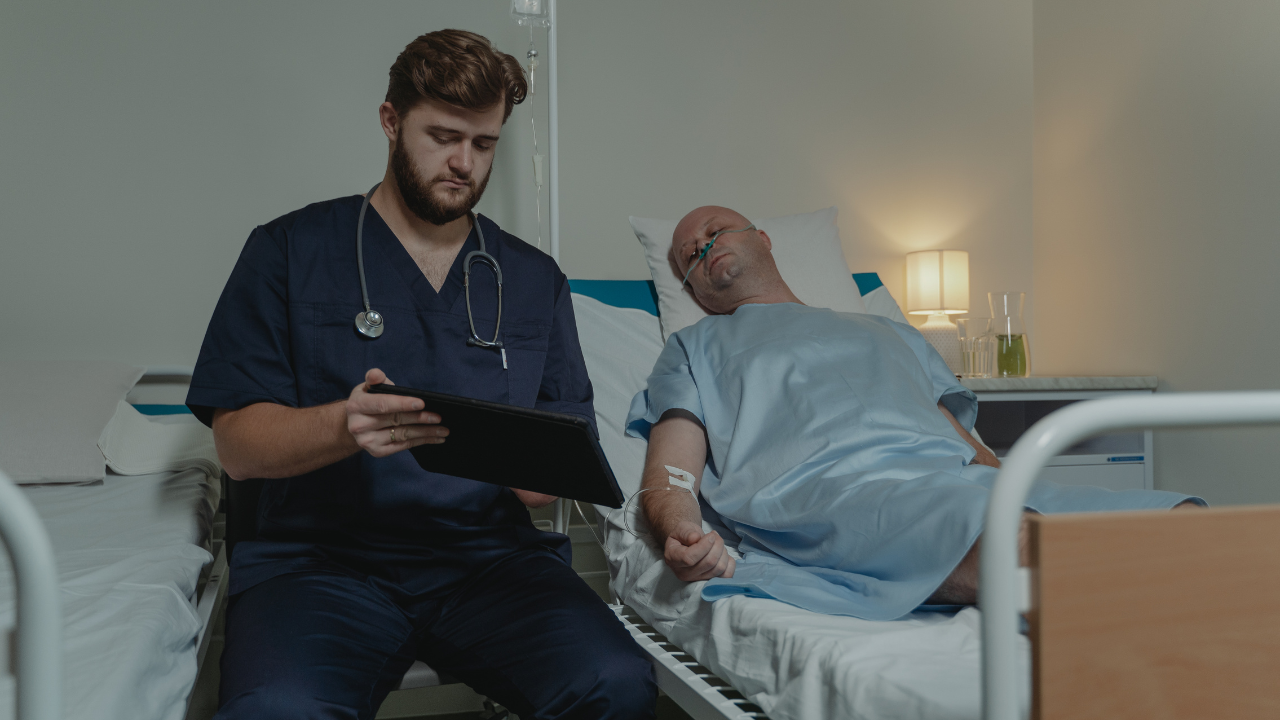Registered nurse reviewing patient information on a tablet while assessing and coordinating care for a hospitalized patient.